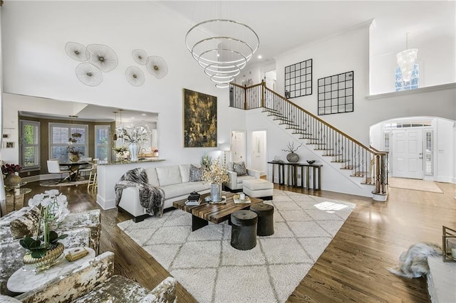 living room featuring stairs, wood finished floors, a towering ceiling, and a notable chandelier