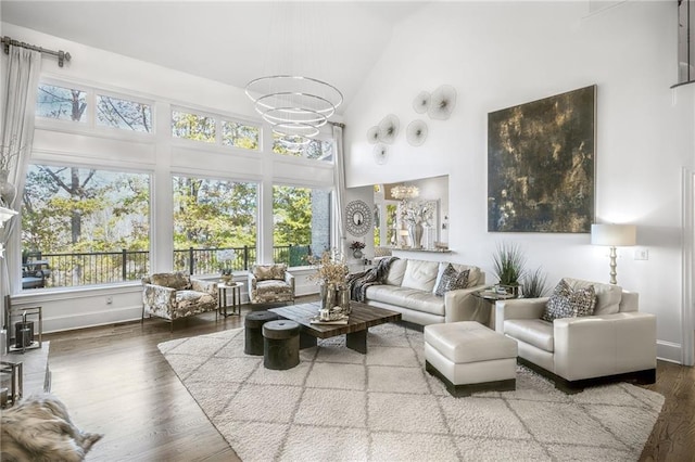 living room with high vaulted ceiling, baseboards, a chandelier, and wood finished floors