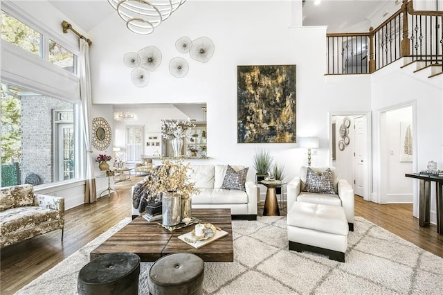 living area with a towering ceiling, stairs, baseboards, and wood finished floors