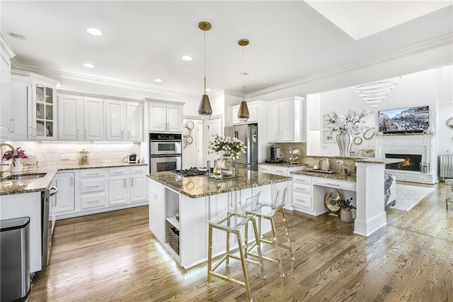 kitchen featuring a kitchen bar, appliances with stainless steel finishes, dark stone counters, and a sink