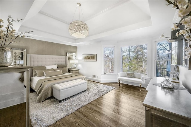 bedroom with a tray ceiling, baseboards, and wood finished floors