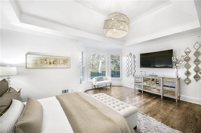 bedroom with baseboards, a tray ceiling, wood finished floors, and crown molding