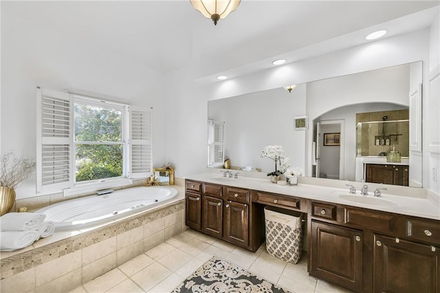 full bathroom with double vanity, a garden tub, a shower stall, and a sink