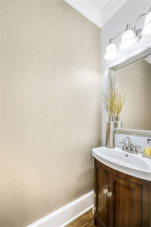 bathroom featuring baseboards, wood finished floors, vanity, and crown molding