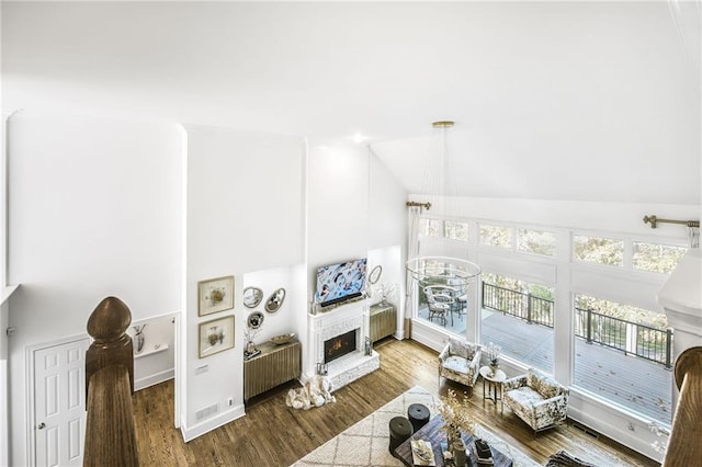 living room with lofted ceiling, a fireplace, radiator heating unit, and wood finished floors