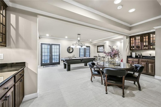 dining area with light carpet, wet bar, ornamental molding, and french doors