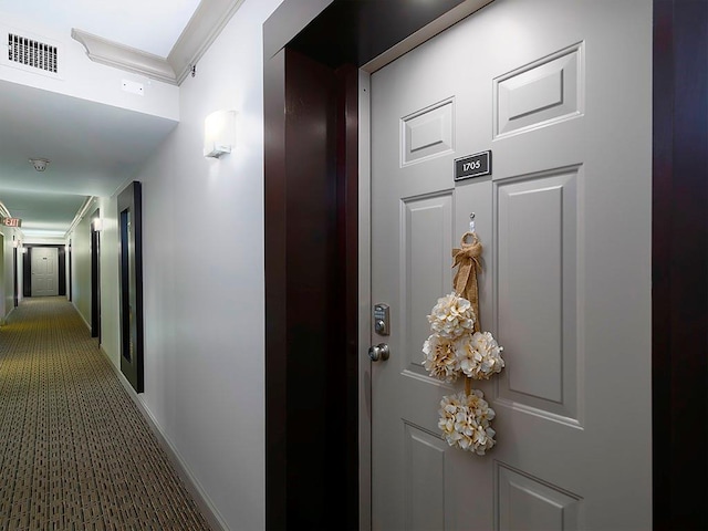 hallway with ornamental molding, carpet, visible vents, and baseboards