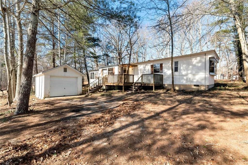 back of house with a garage, an outbuilding, and a deck