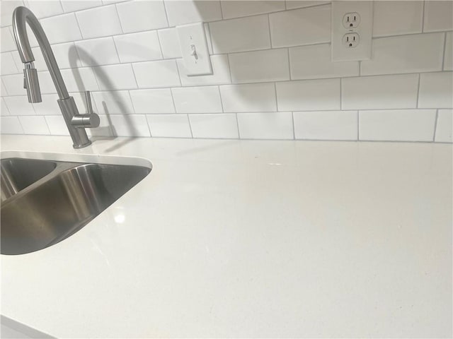 interior details featuring decorative backsplash, light countertops, and a sink