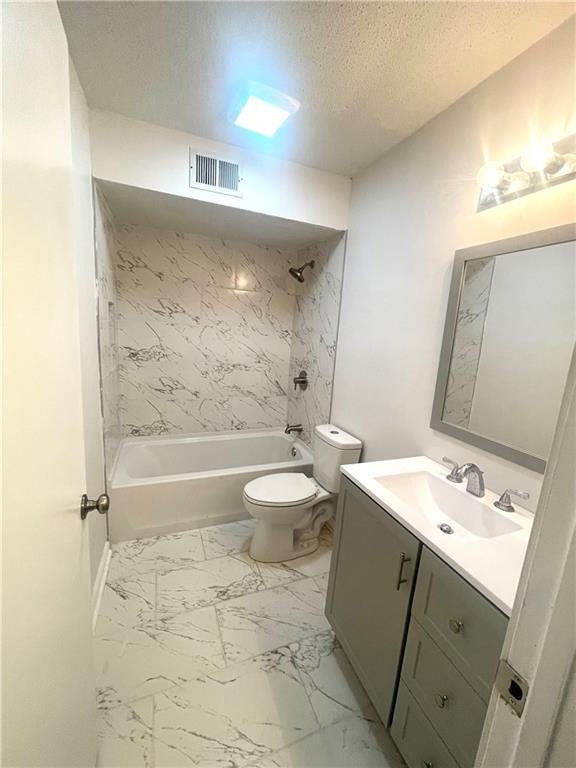 full bathroom featuring visible vents, toilet, bathtub / shower combination, marble finish floor, and a textured ceiling