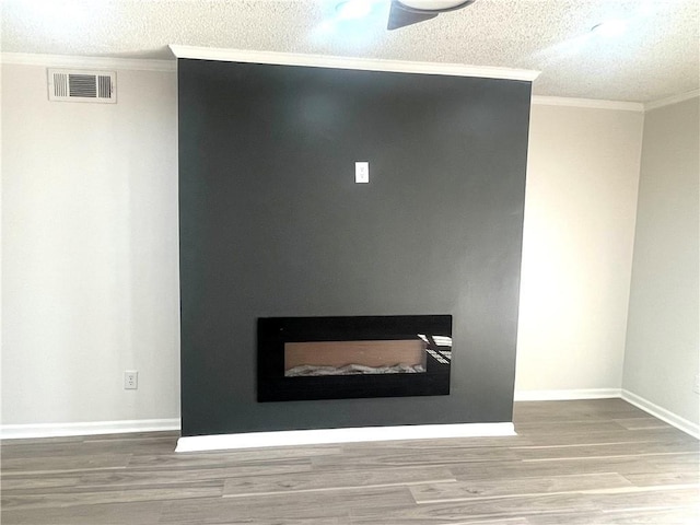 room details with wood finished floors, baseboards, visible vents, a textured ceiling, and crown molding