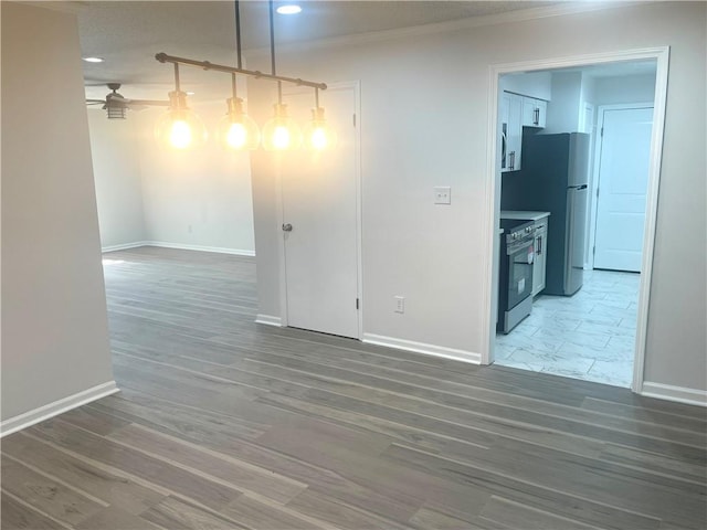 empty room featuring wood finished floors, baseboards, and ornamental molding