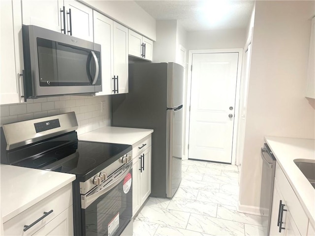 kitchen with stainless steel appliances, light countertops, white cabinets, marble finish floor, and tasteful backsplash