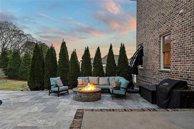 patio terrace at dusk with area for grilling and an outdoor living space with a fire pit