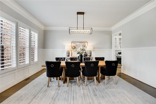 dining space with wood-type flooring and ornamental molding