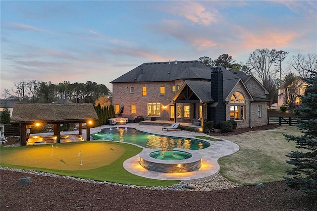 pool at dusk with a gazebo, a patio, and an in ground hot tub