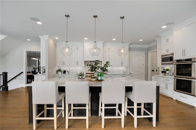 kitchen featuring appliances with stainless steel finishes, a large island, a kitchen breakfast bar, and white cabinets