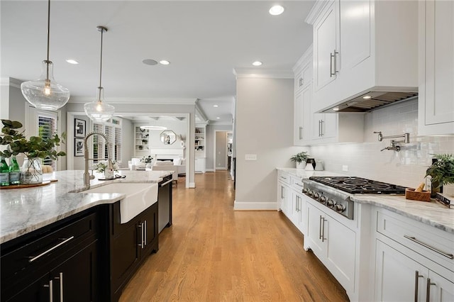 kitchen with white cabinetry, sink, pendant lighting, and light stone counters