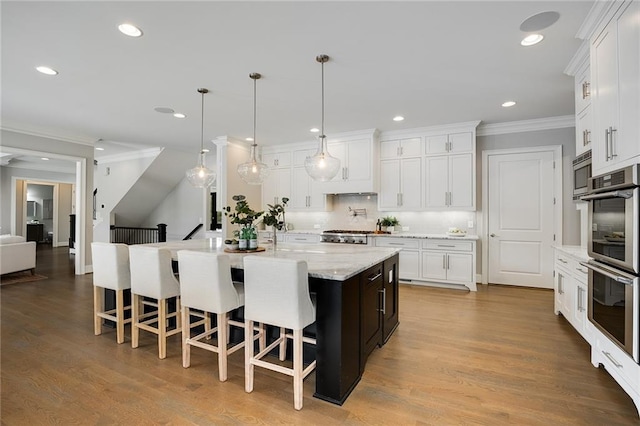 kitchen featuring a large island with sink, white cabinetry, pendant lighting, and a kitchen breakfast bar