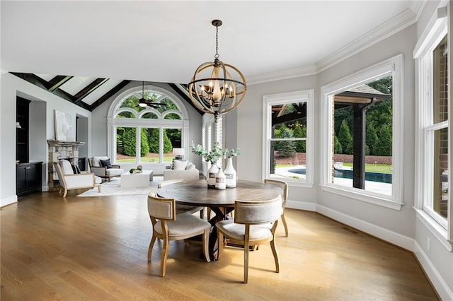 dining area with wood-type flooring, vaulted ceiling, a healthy amount of sunlight, and a notable chandelier