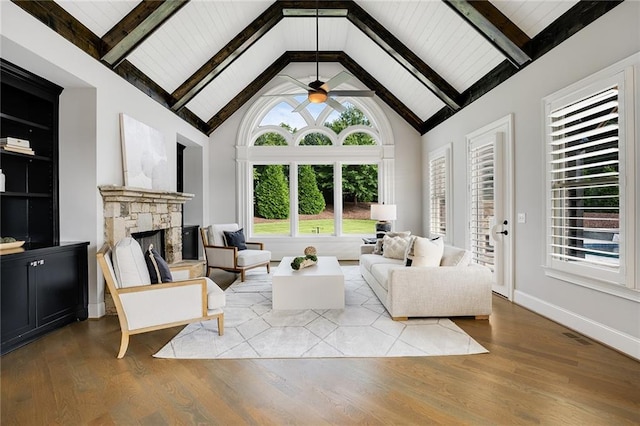 living room featuring a stone fireplace, high vaulted ceiling, ceiling fan, and light hardwood / wood-style flooring