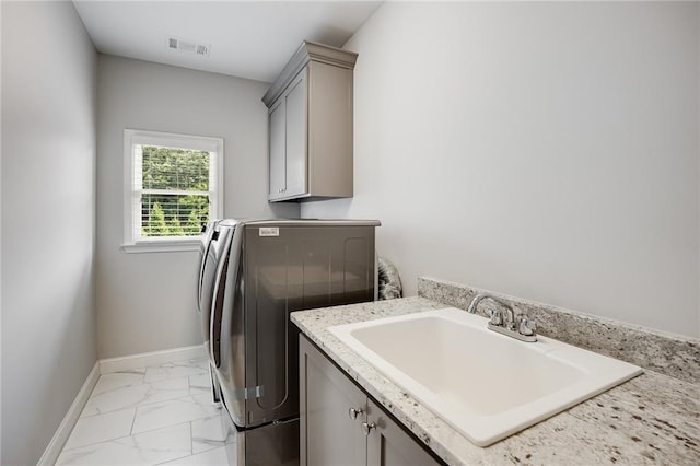 clothes washing area featuring cabinets, sink, and washing machine and clothes dryer