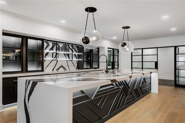 kitchen featuring a spacious island, ornamental molding, light hardwood / wood-style floors, and decorative light fixtures