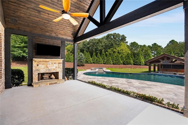 view of pool featuring a patio, ceiling fan, and an outdoor stone fireplace