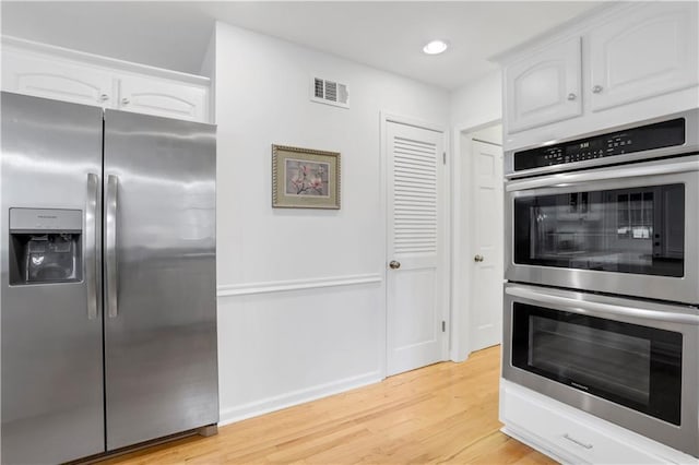 kitchen featuring appliances with stainless steel finishes, white cabinets, and light hardwood / wood-style flooring