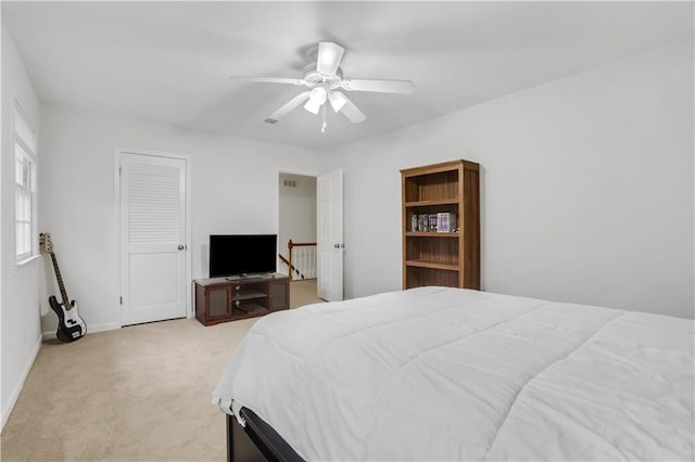 bedroom with ceiling fan, a closet, and light carpet