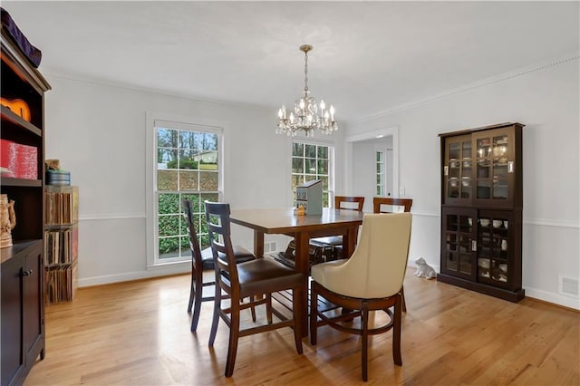 dining area with a notable chandelier, crown molding, and light hardwood / wood-style floors