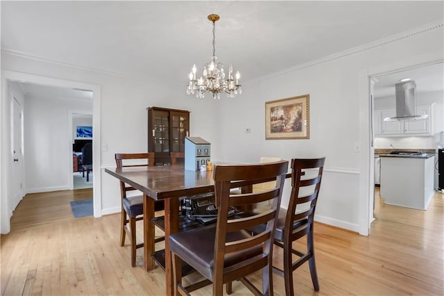 dining area featuring crown molding, a chandelier, and light wood-type flooring