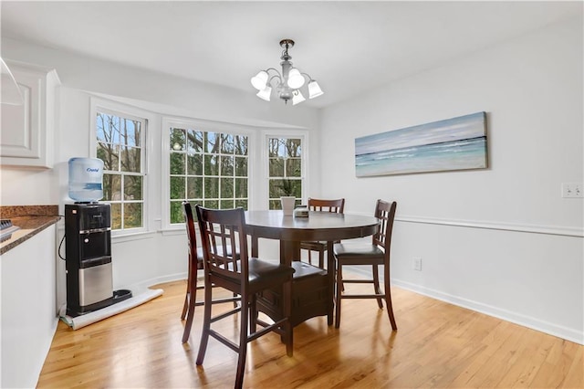 dining area with light hardwood / wood-style flooring and a notable chandelier