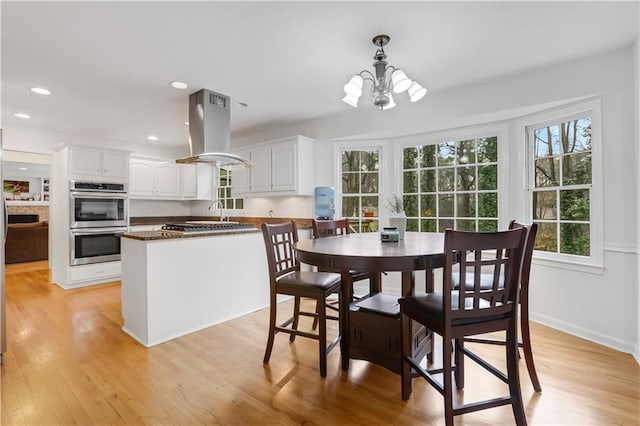 dining area with a healthy amount of sunlight, a chandelier, and light wood-type flooring