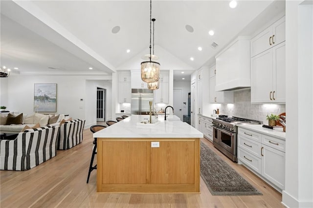 477 Michael Dr, Alpharetta, GA 30009 - kitchen featuring high end appliances, open floor plan, backsplash, a chandelier, and light wood finished floors