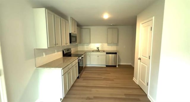 45 Emerald Ln, Covington, GA 30014 - kitchen with appliances with stainless steel finishes, a sink, decorative backsplash, light wood-type flooring, and baseboards