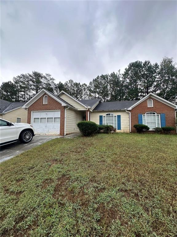 ranch-style home with a garage and a front lawn