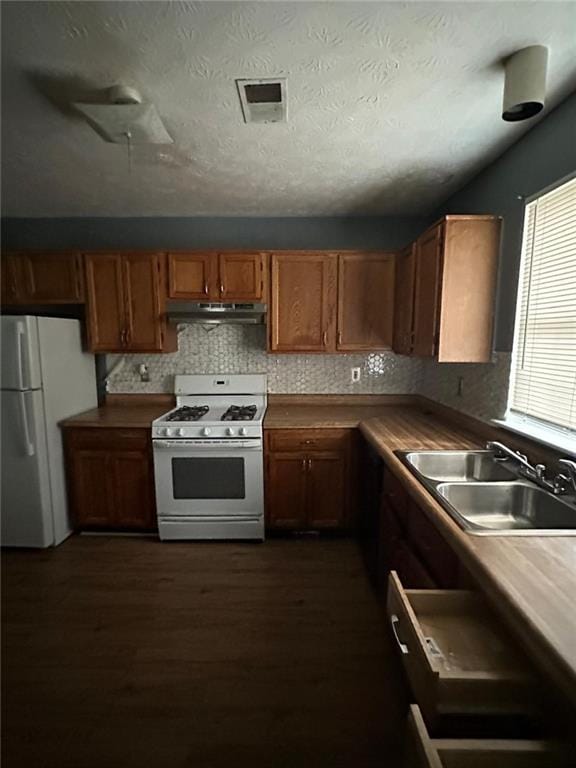 kitchen featuring dark hardwood / wood-style flooring, white appliances, sink, and tasteful backsplash