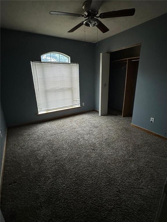 unfurnished bedroom with ceiling fan, carpet floors, and a closet