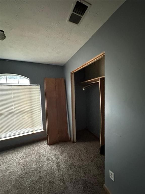 unfurnished bedroom featuring dark colored carpet, a textured ceiling, and a closet