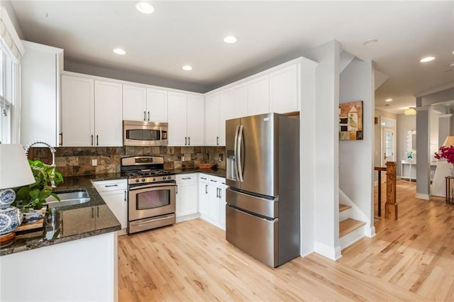 kitchen featuring white cabinets, appliances with stainless steel finishes, tasteful backsplash, and dark stone countertops