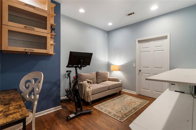 living area featuring baseboards, visible vents, and wood finished floors