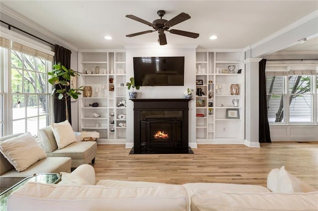living area featuring plenty of natural light, ornamental molding, and wood finished floors