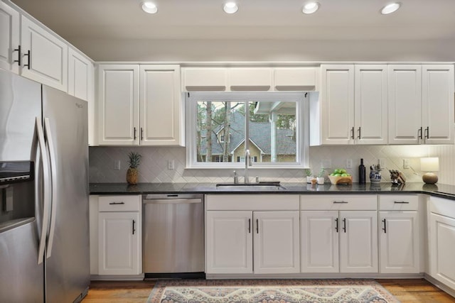 kitchen featuring a sink, dark countertops, light wood-type flooring, and stainless steel appliances