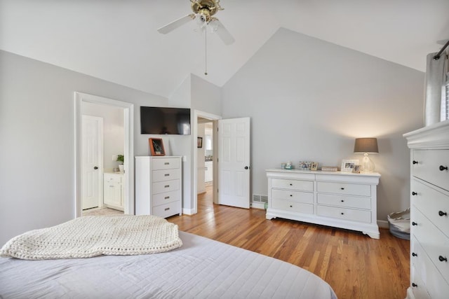 bedroom with high vaulted ceiling, a ceiling fan, ensuite bath, wood finished floors, and baseboards