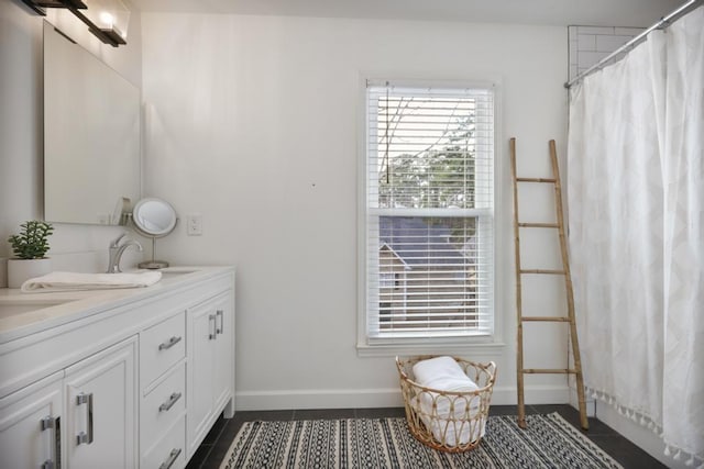 bathroom featuring tile patterned floors, a sink, curtained shower, double vanity, and baseboards