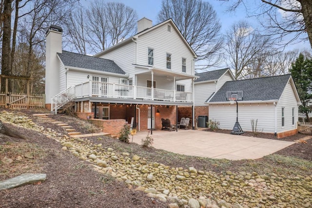 back of house featuring central air condition unit, stairway, a chimney, and a patio area