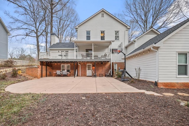 back of house with a patio area, a ceiling fan, brick siding, and a chimney