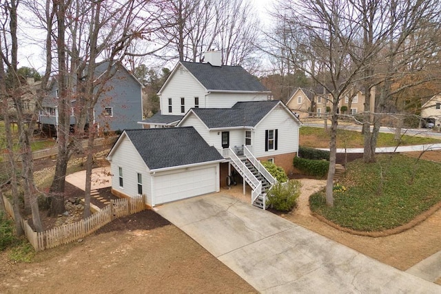 traditional home featuring fence, driveway, a shingled roof, stairs, and a garage