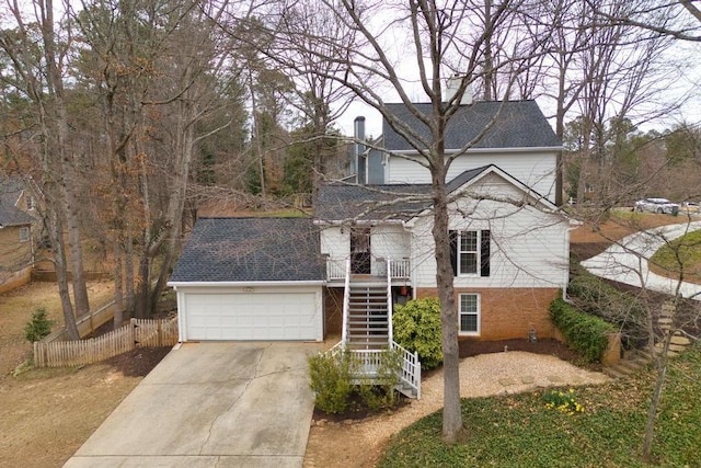 traditional-style home with fence, stairs, concrete driveway, a garage, and brick siding